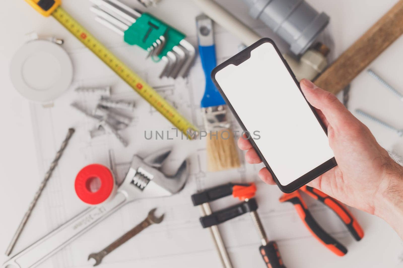 Smartphone with blank screen with drawing and building supplies in the background