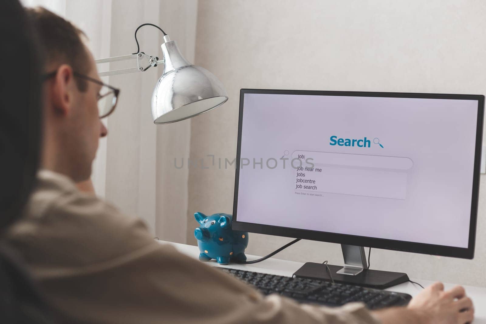 Unemployed man looking for work on the Internet sitting at a computer at home.