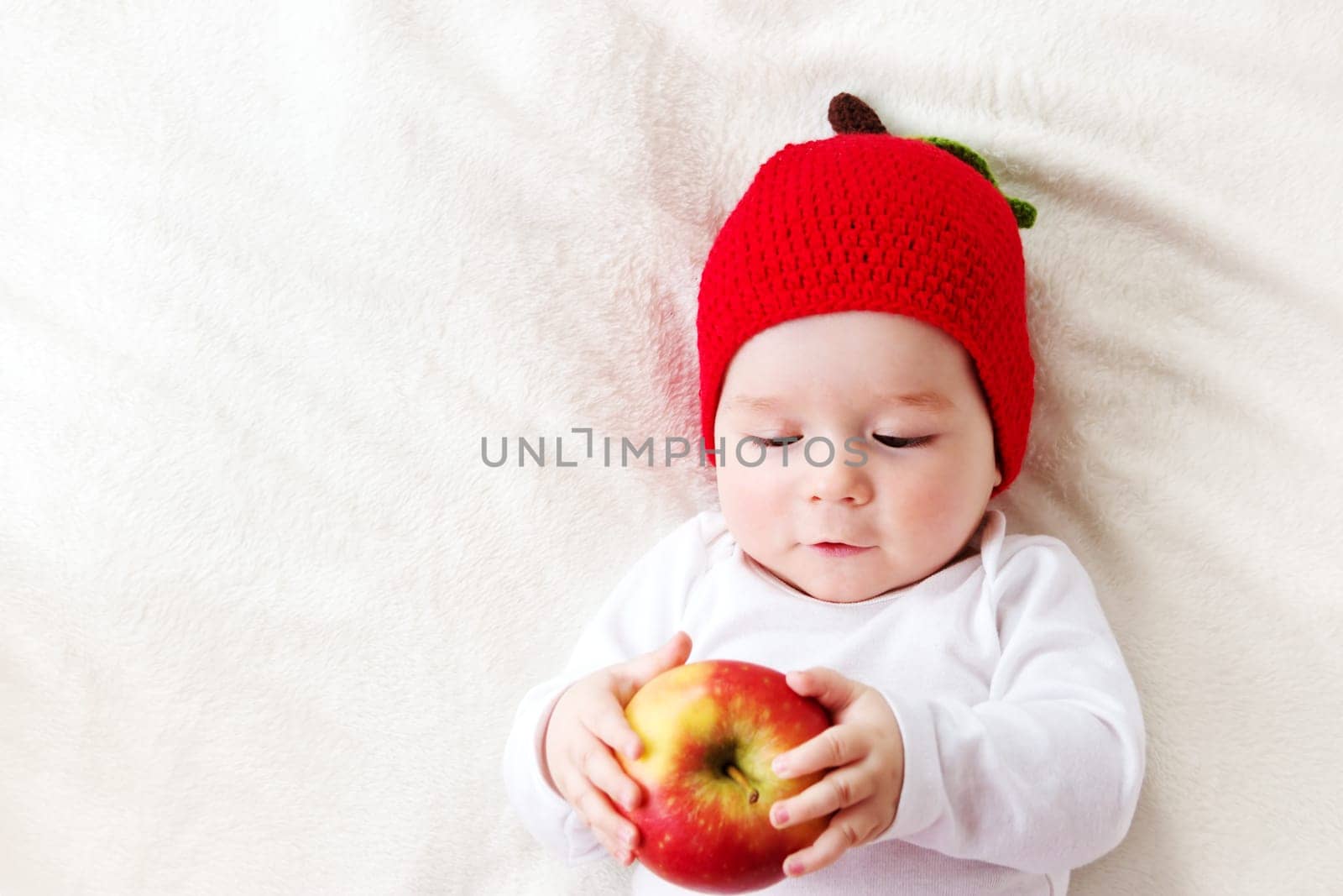 7 month old baby lying inbed with apple