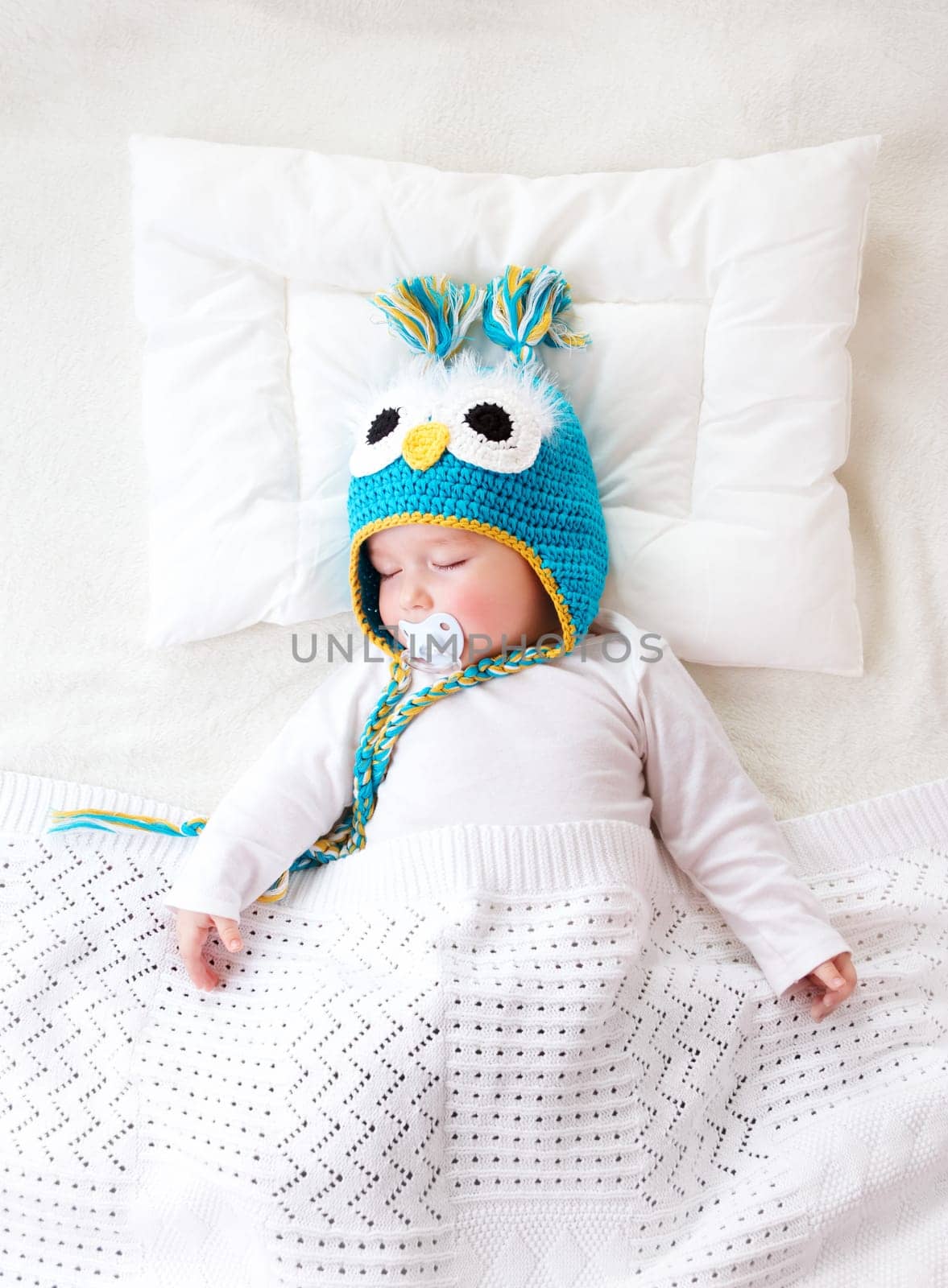 seven month old boy sleeping in the bed in owl hat