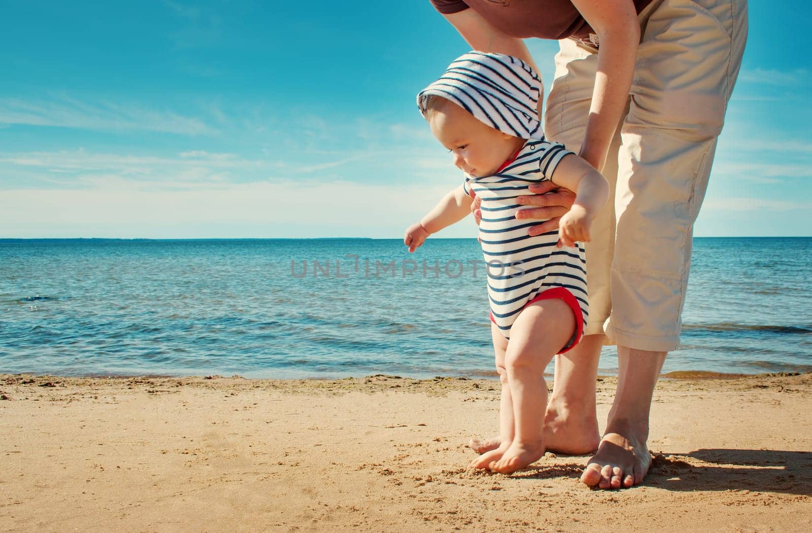 Nine month old baby boy walking on the beach in beautiful summer day