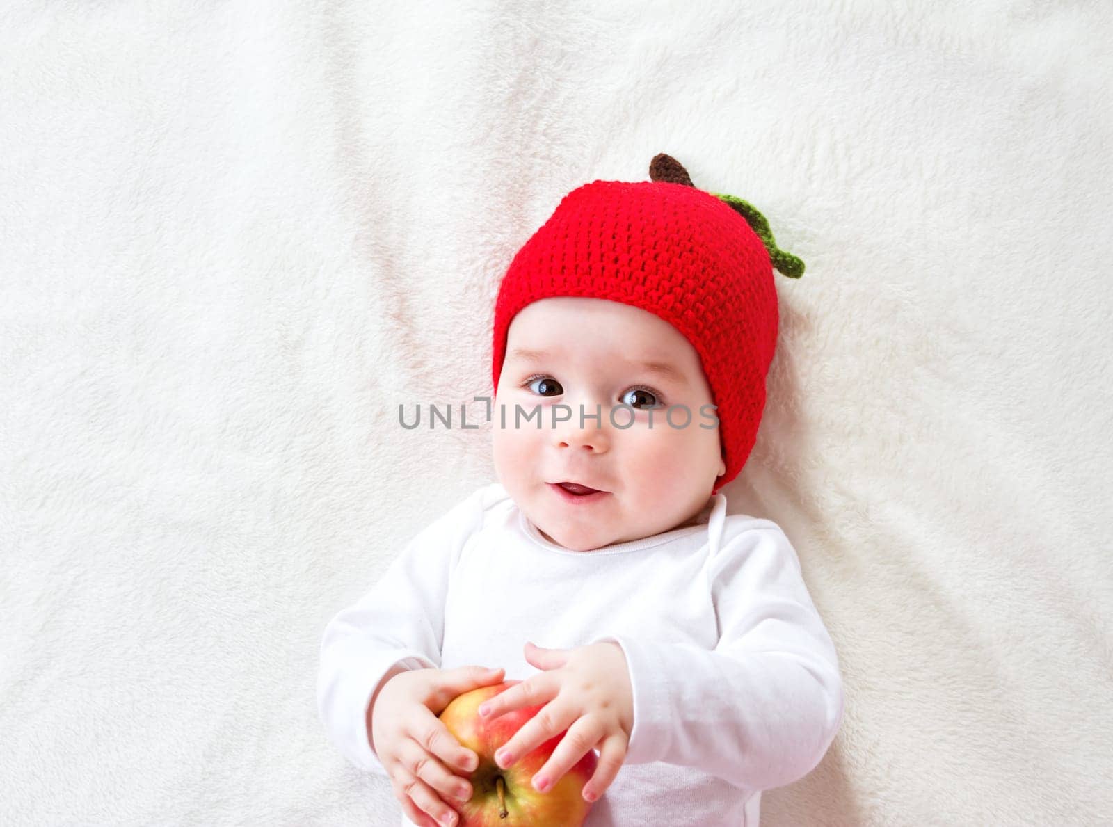 7 month old baby lying inbed with apple