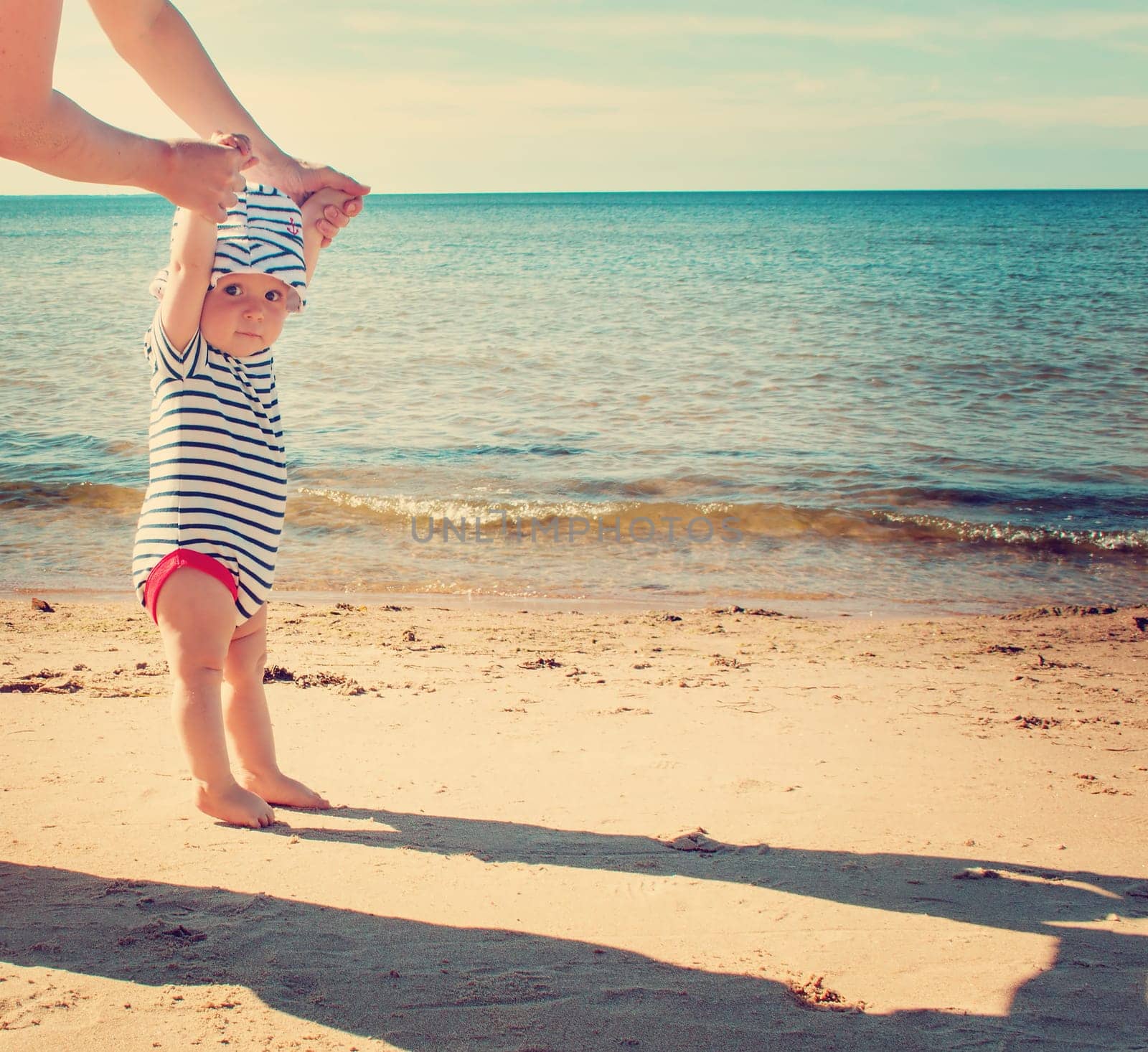 Nine month old baby boy walking on the beach in beautiful summer day