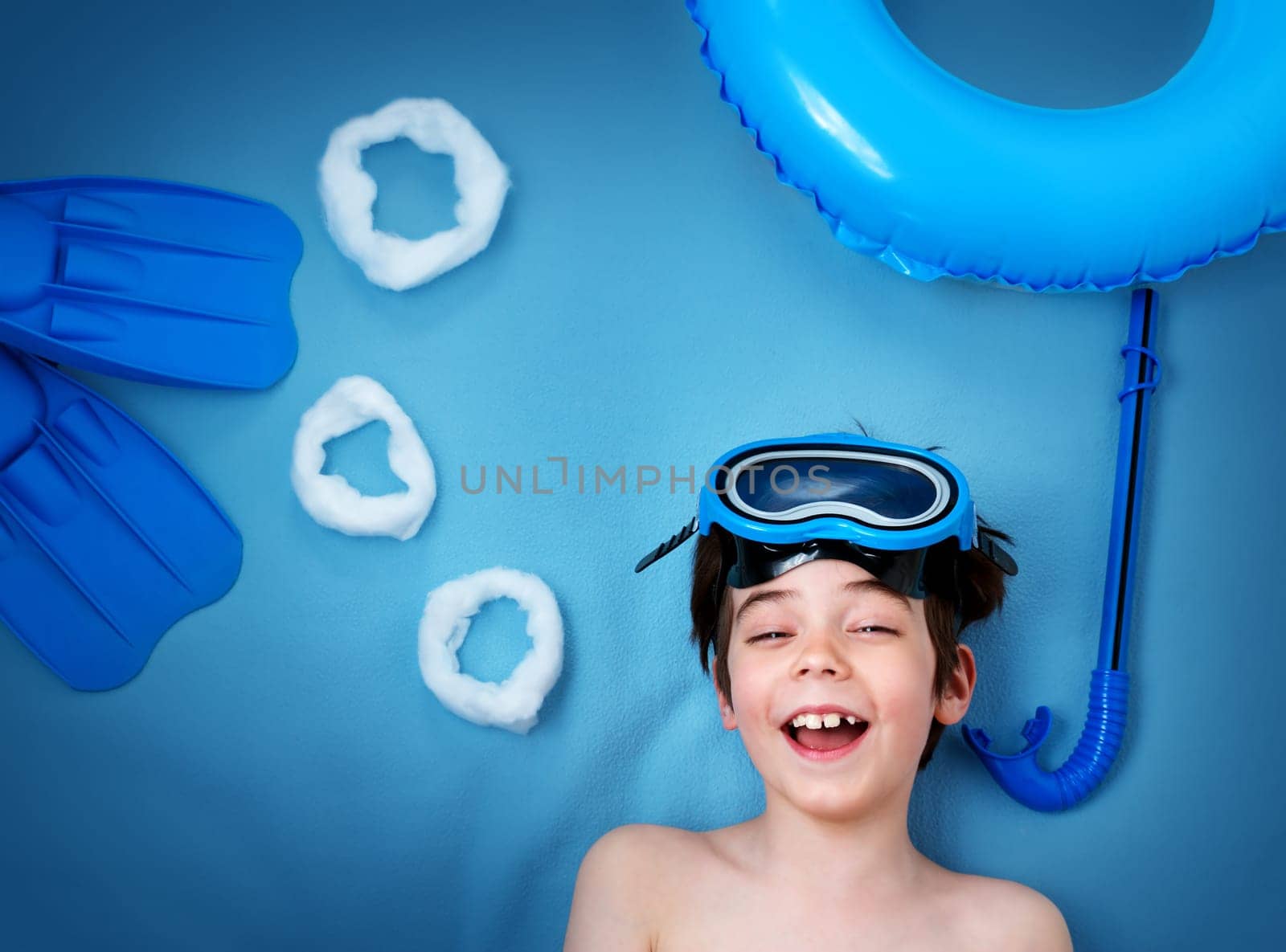 Child lying on blue blanket with swimming mask and flippers