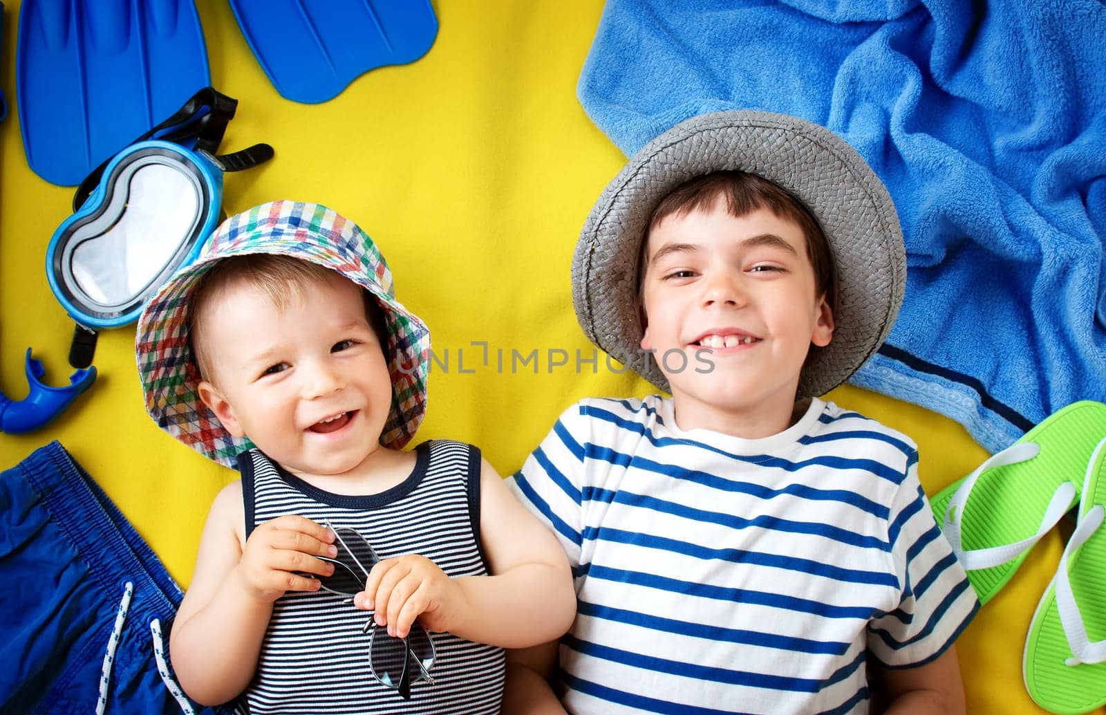 little boy with sunglasses in hat on yellow blanket