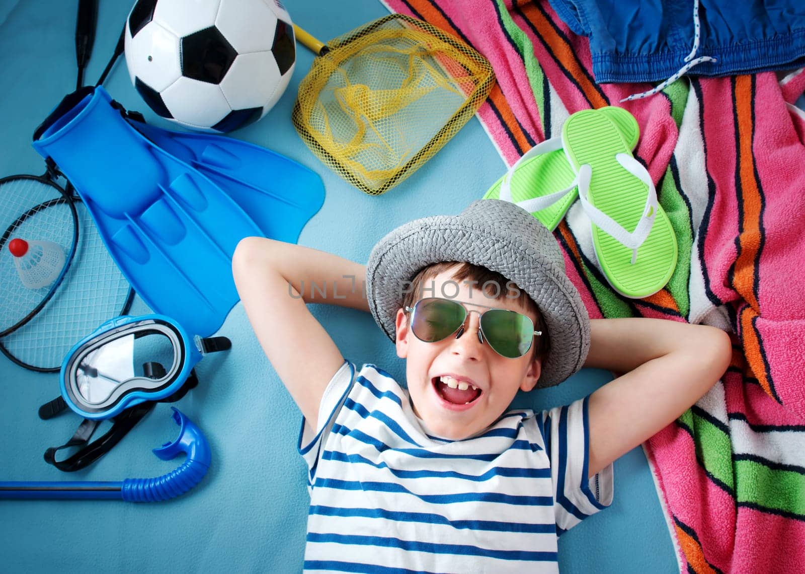 boy with sunglasses and toys on blue blanket