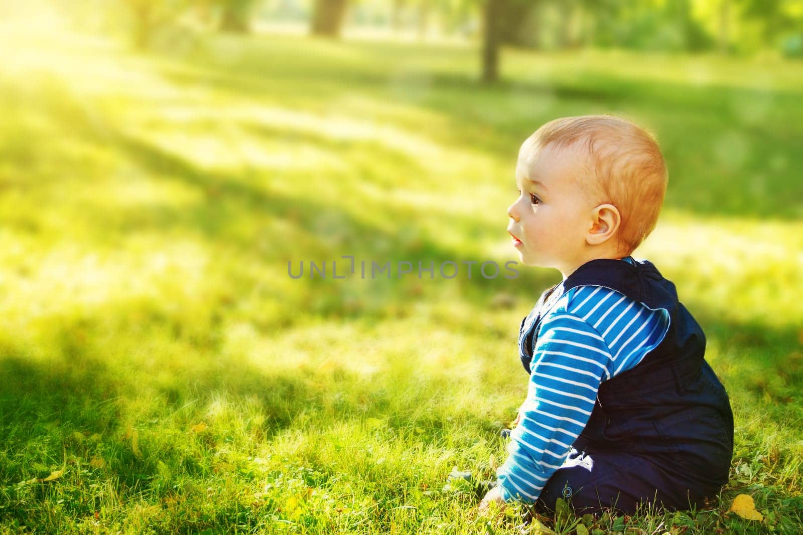 little nine month old baby sitting in the park in beautiful evening