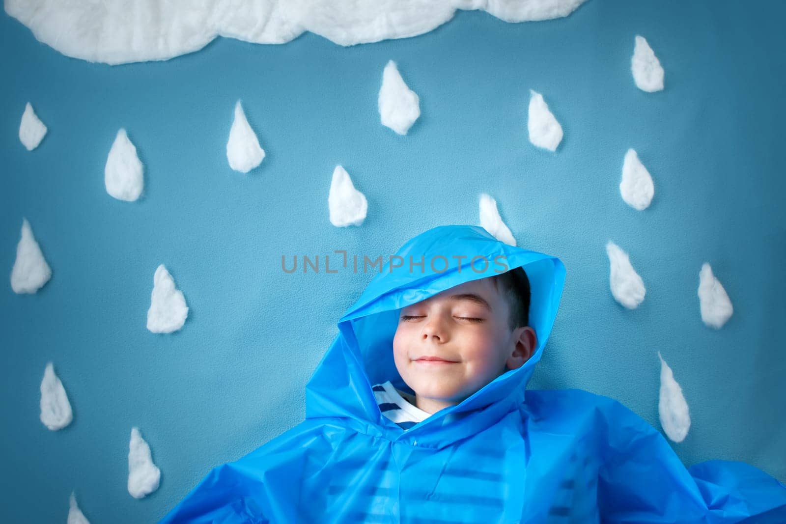 boy on blue background in coat with drop shapes and cloud