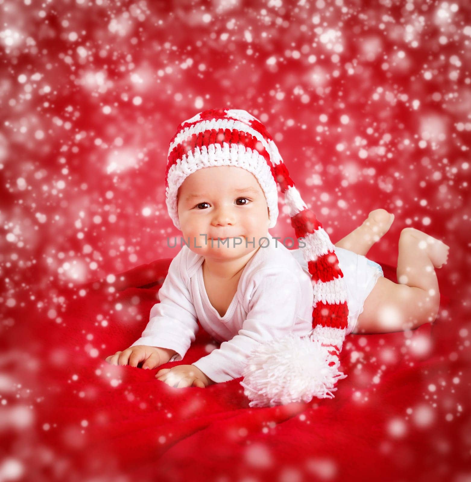 little baby in knitted red whitey hat on red blanket