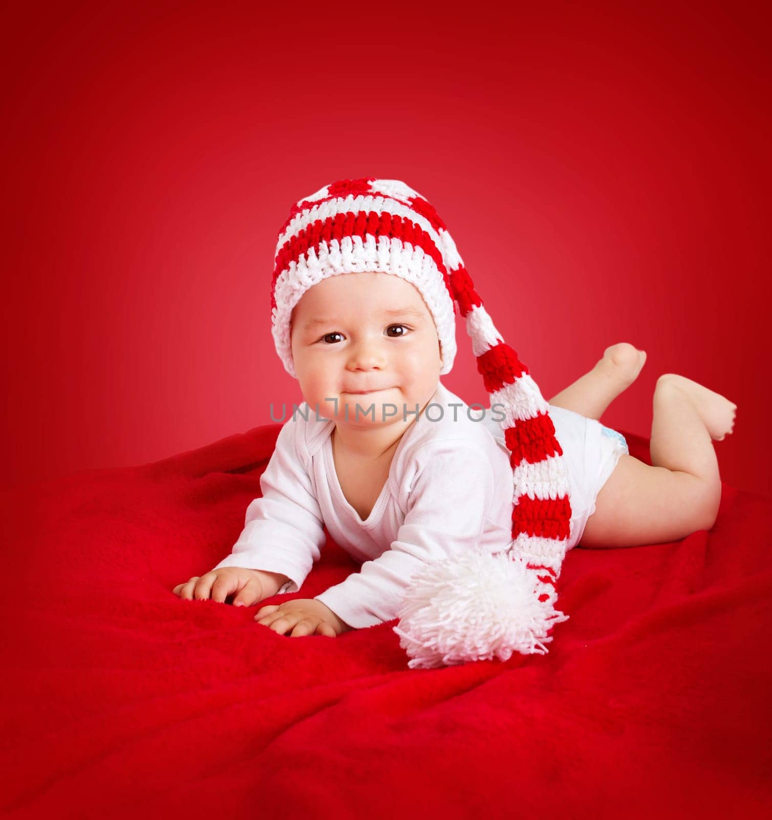 little baby in knitted red whitey hat on red blanket