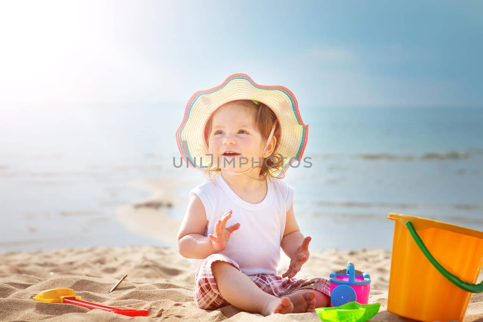 one year old girl shouting at the sea with bucket