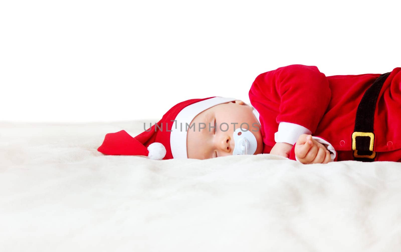little baby sleeping in red hat on white blanket. Eight month old child in santa costume