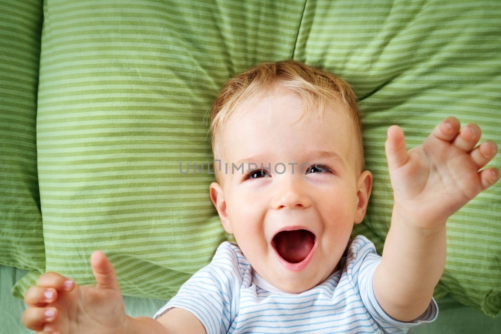One year old baby lying in the bed with green bedding