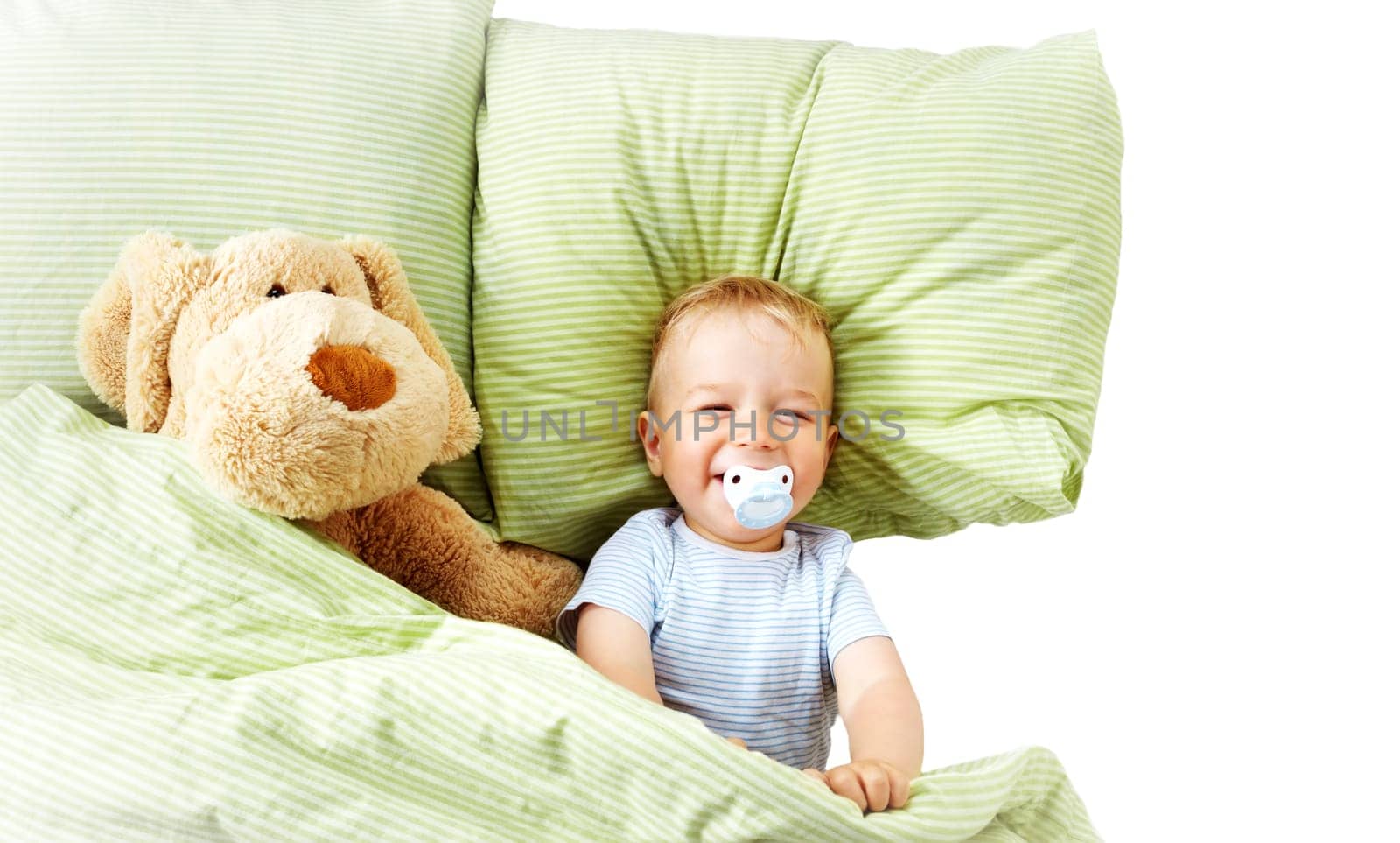 One year old baby lying in the bed with green bedding with soft toy