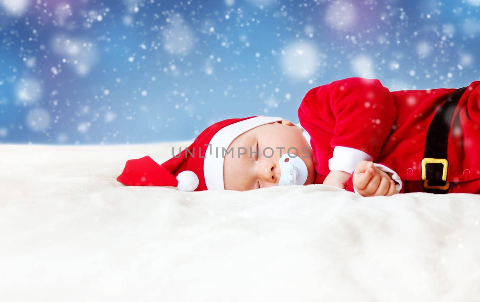 little baby sleeping in red hat on white blanket. Eight month old child in santa costume