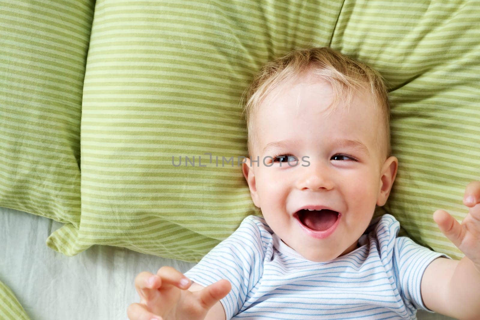 One year old baby lying in the bed with green bedding