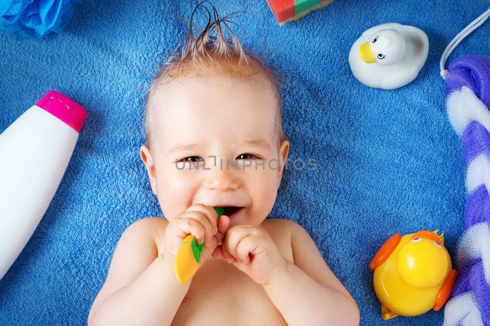 one year old baby lying on towel with washing tools