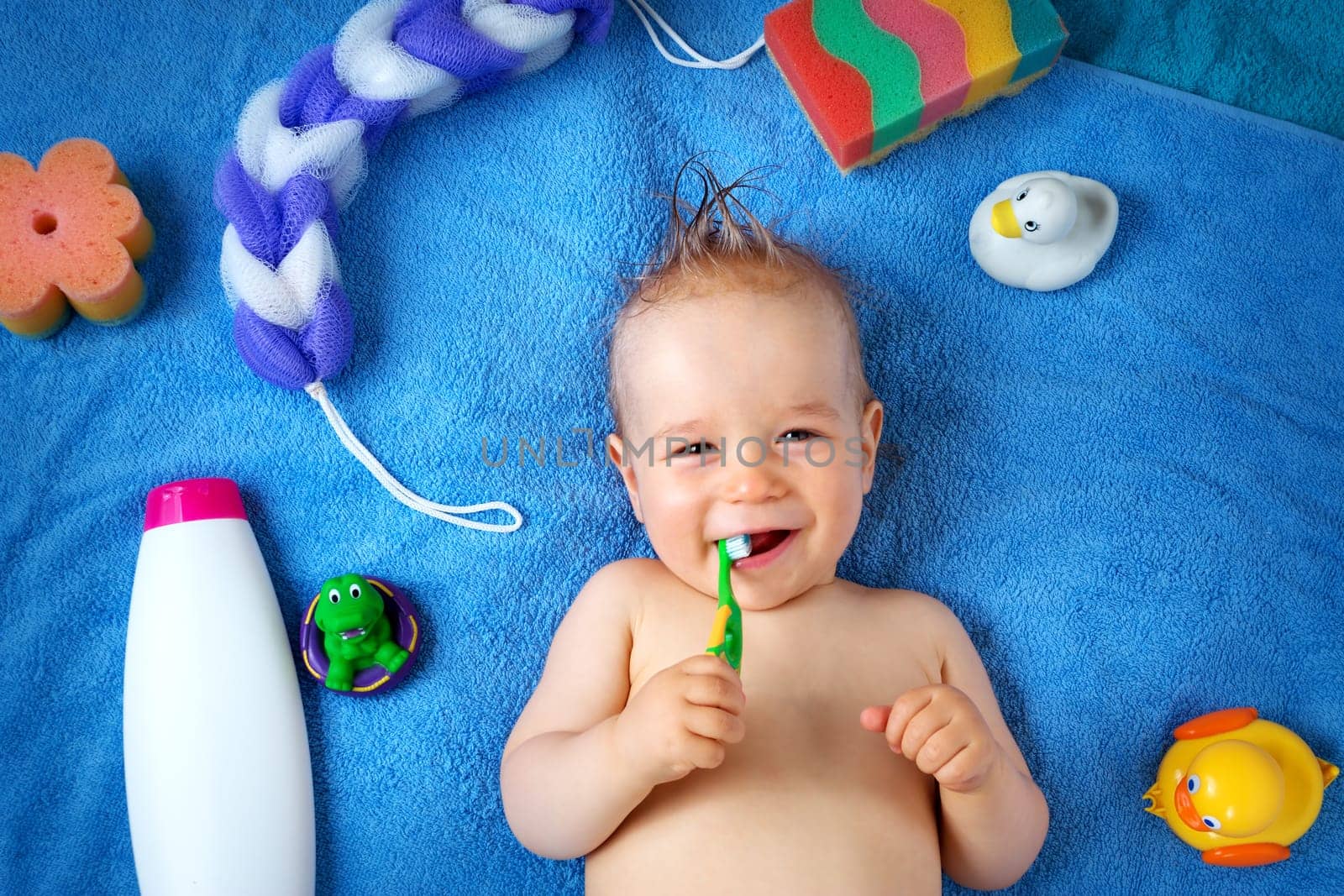 one year old baby lying on towel with washing tools