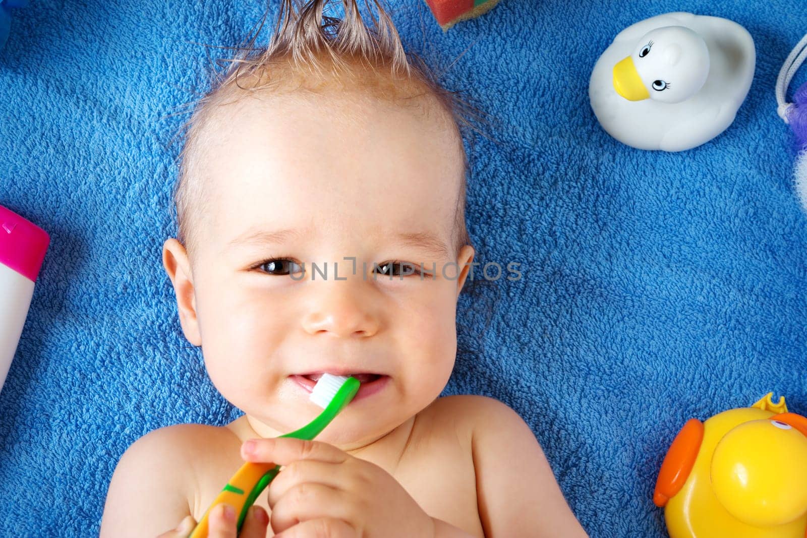 one year old baby lying on towel with washing tools