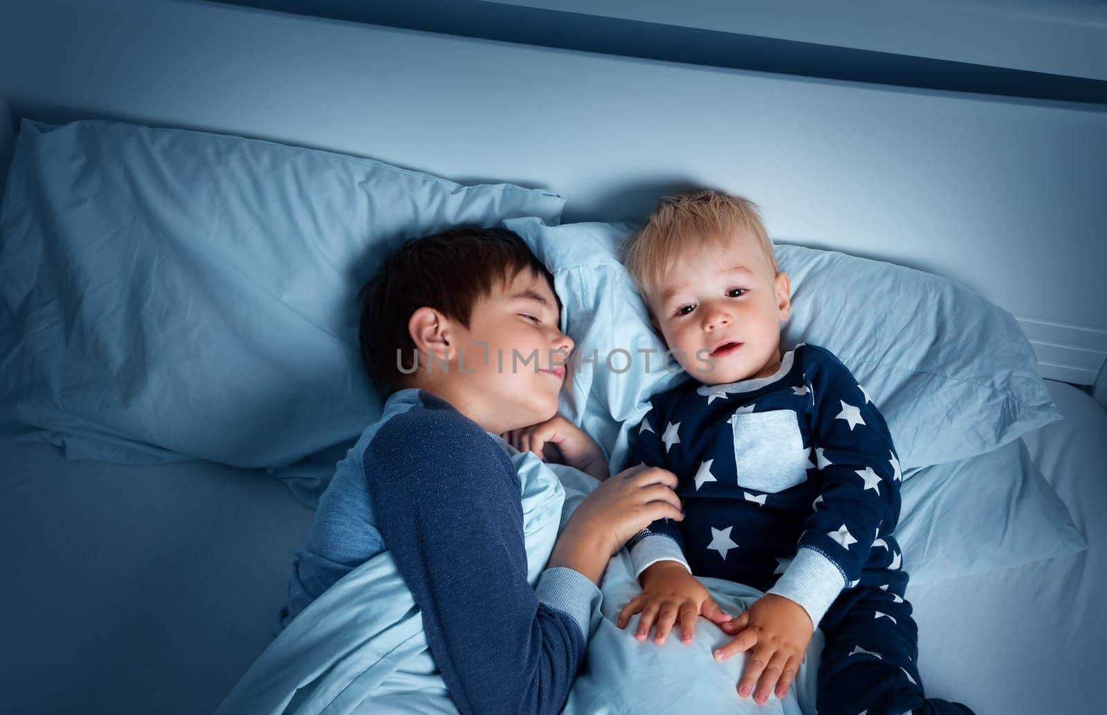 children lying in bed at night. Brothers going to sleep