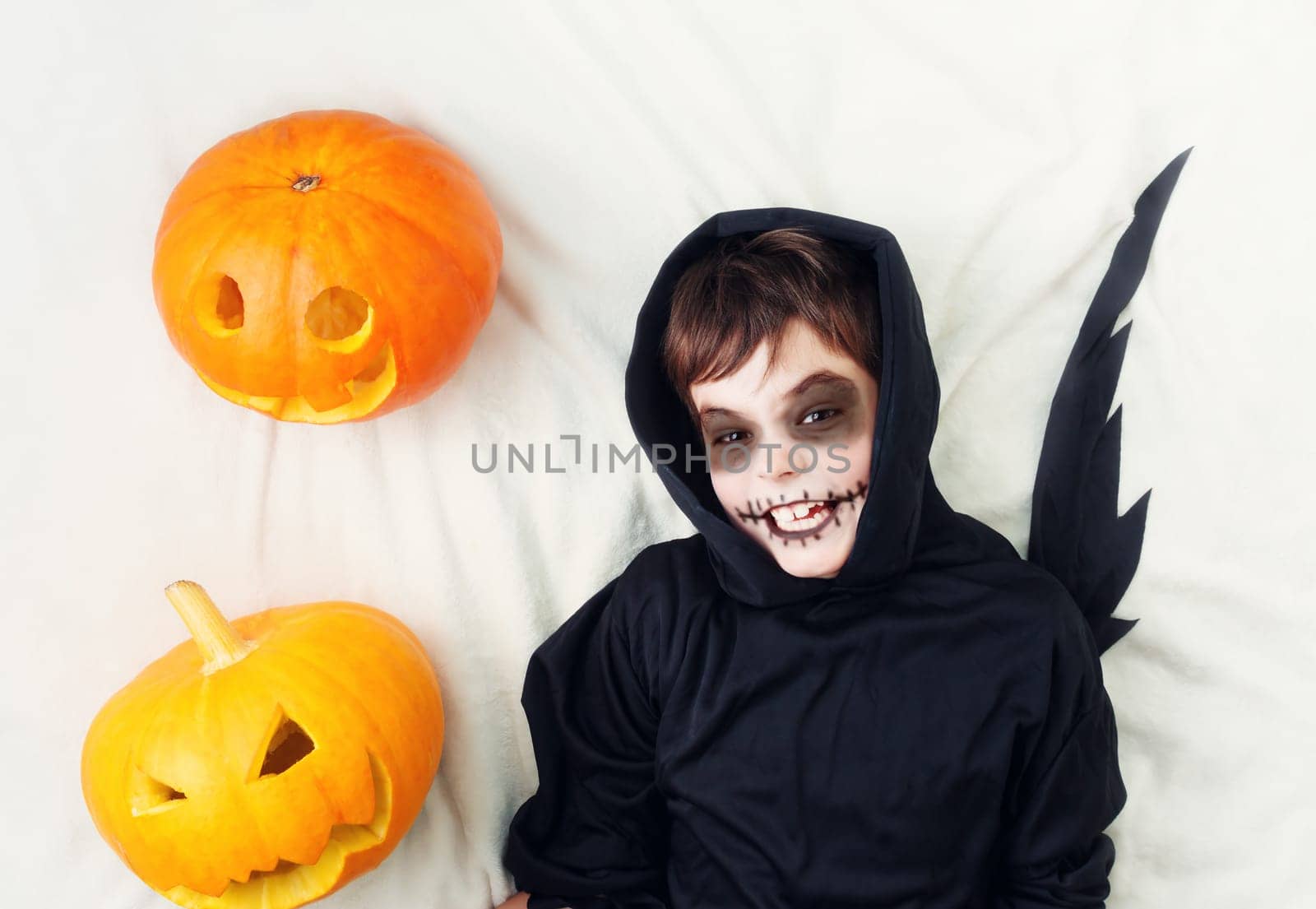 Child in scary costume with pumpkin. Child in halloween outfit on white background