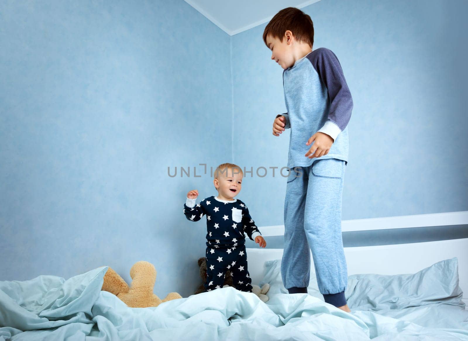 One year old baby in pyjamas lying in the bed with blue bedding