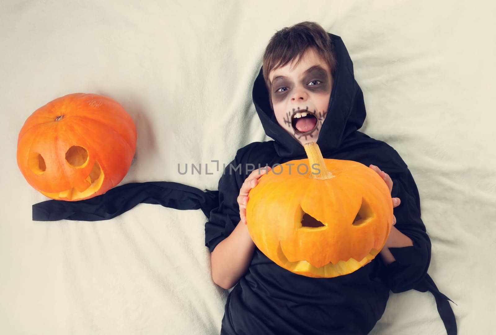 Child in scary costume with pumpkin. Child in halloween outfit on white background