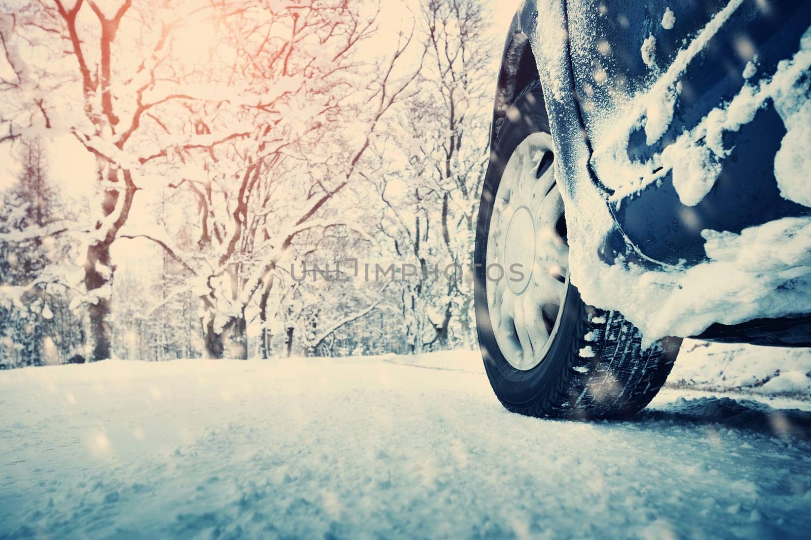 Car tires on winter road covered with snow. Vehicle on snowy alley in the morning at snowfall