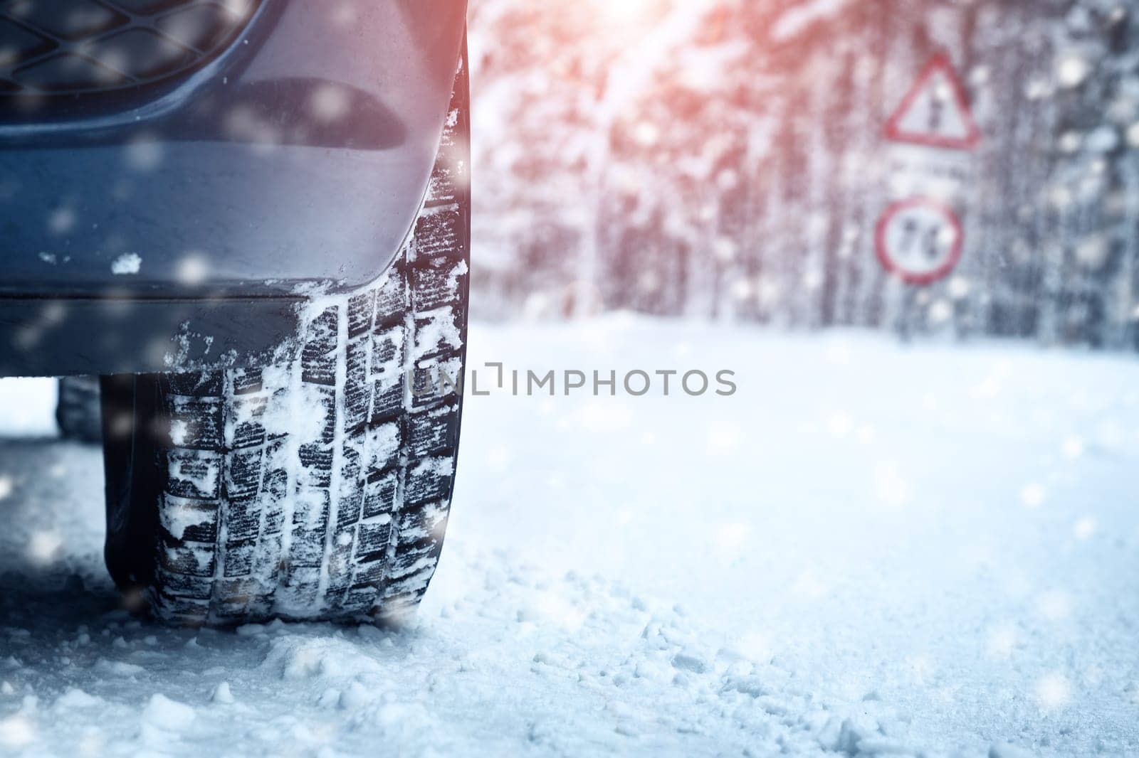 Car tires on winter road covered with snow. Vehicle on snowy alley in the morning at snowfall