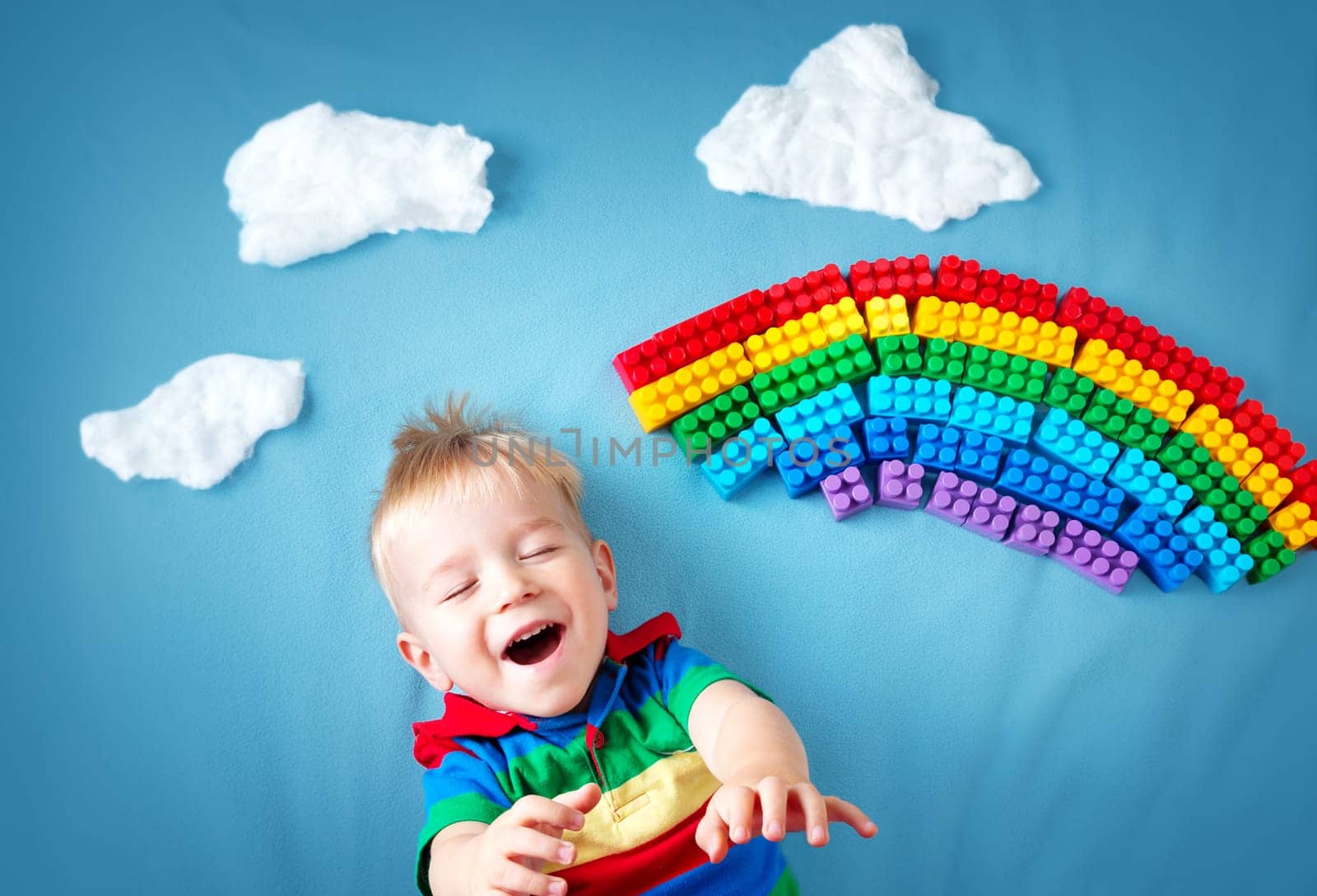 Baby boy lying on blue blanket with rainbow and clouds