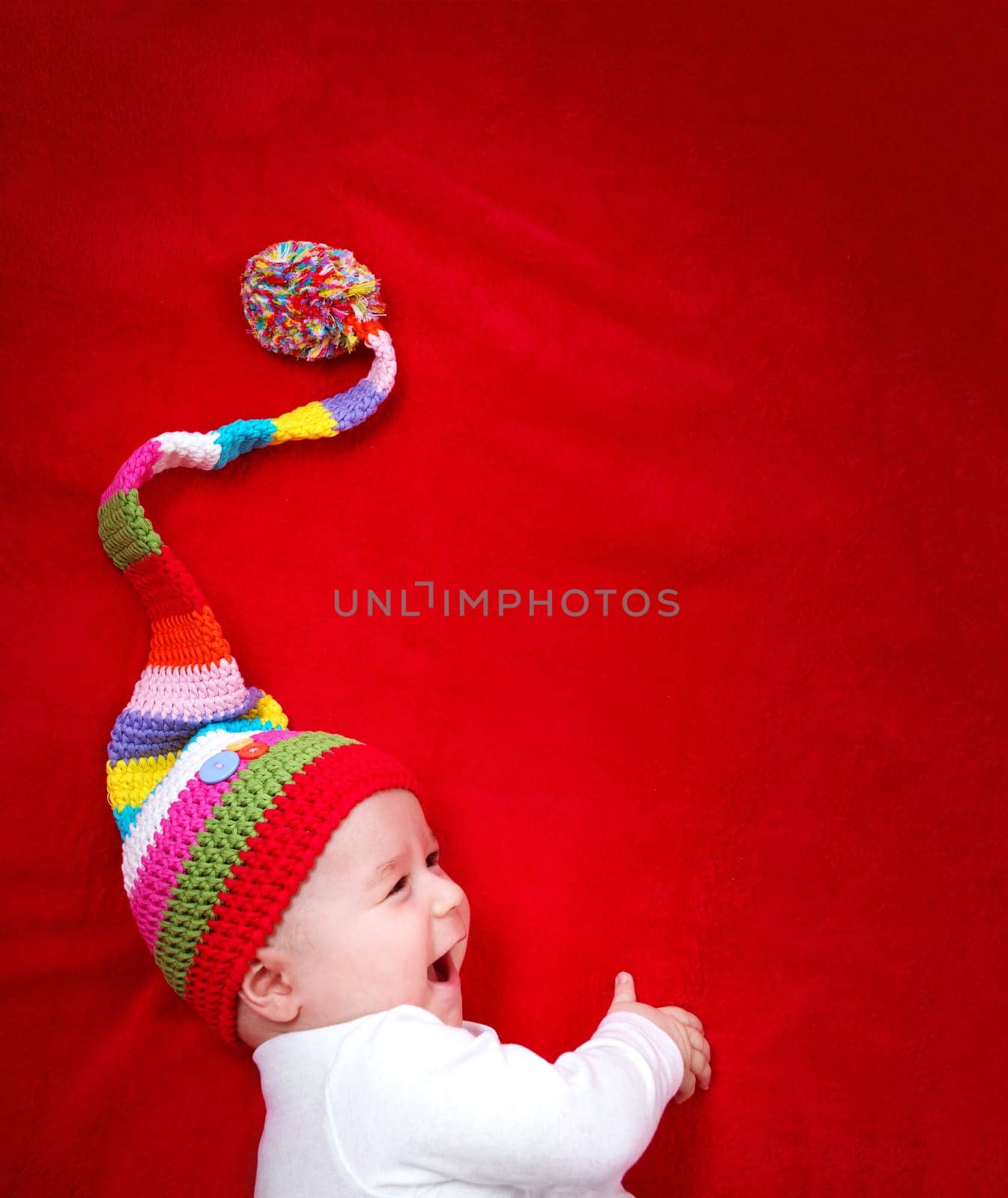 Baby in colorful hat on the bed