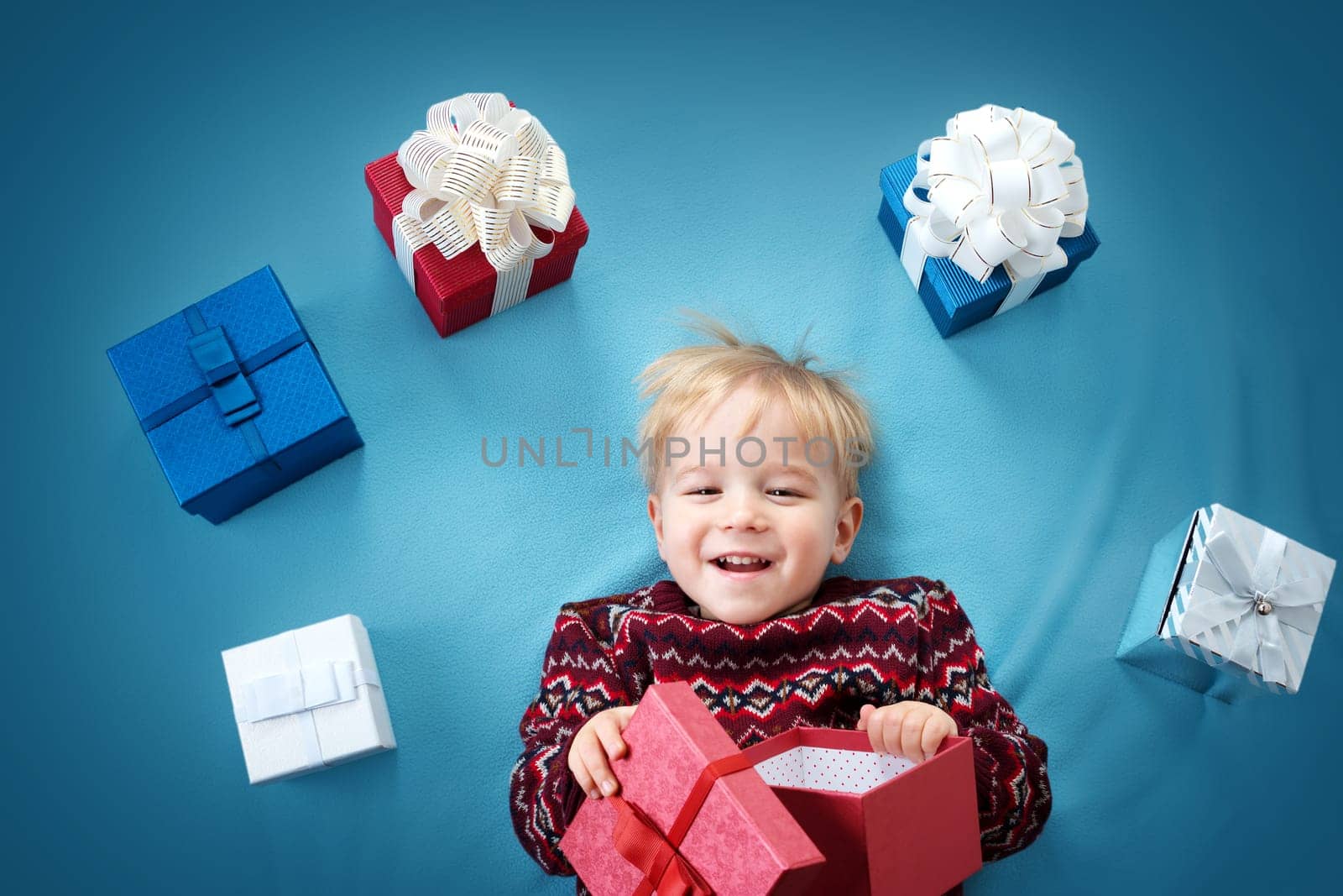 Happy child on blue blanket. Cute boy with many presents