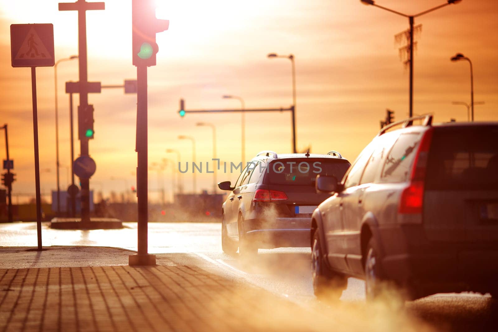 Cars moving on the road in city in early morning. View to the traffic with trafficlights and transport