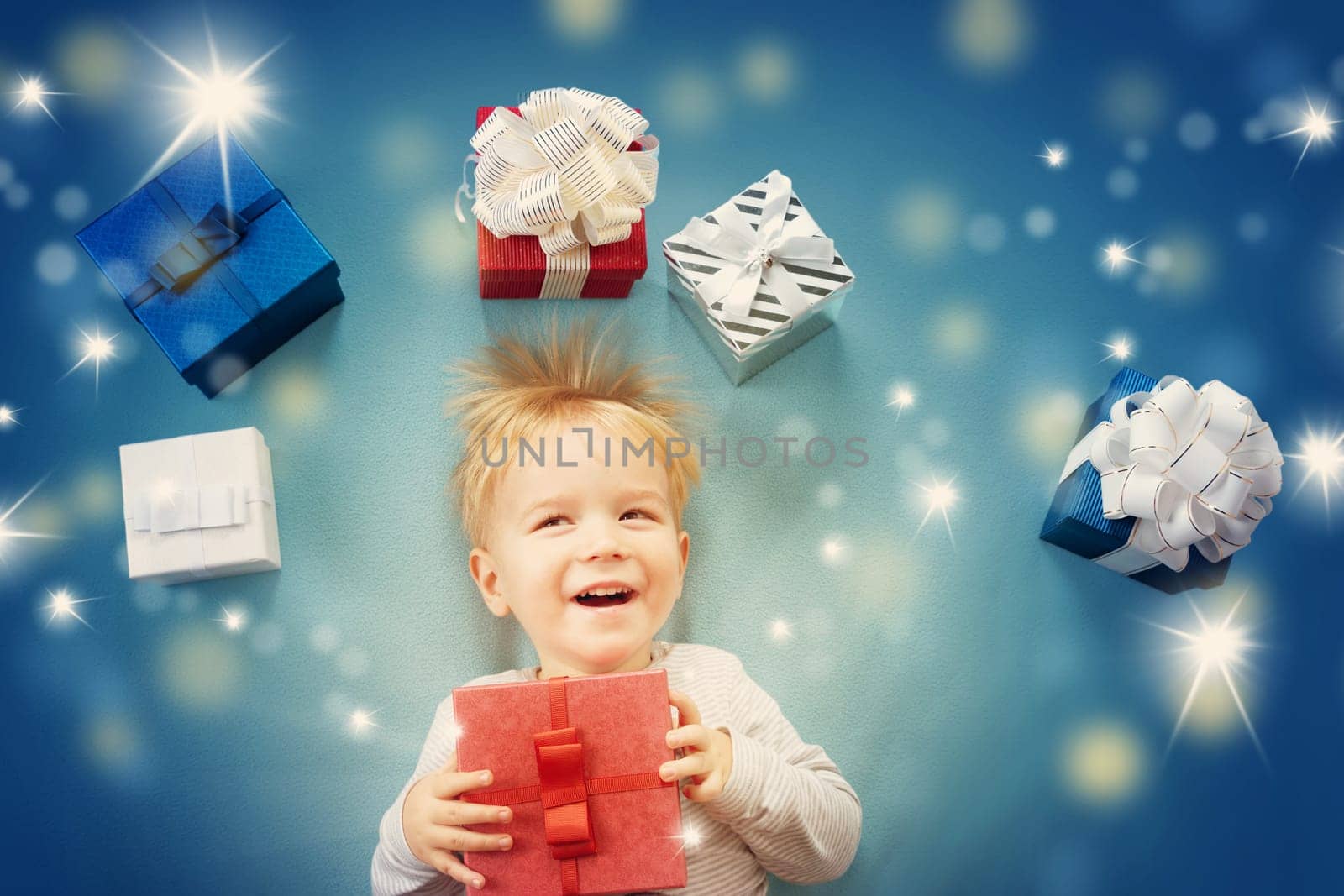 Happy child on blue blanket. Cute boy with many presents