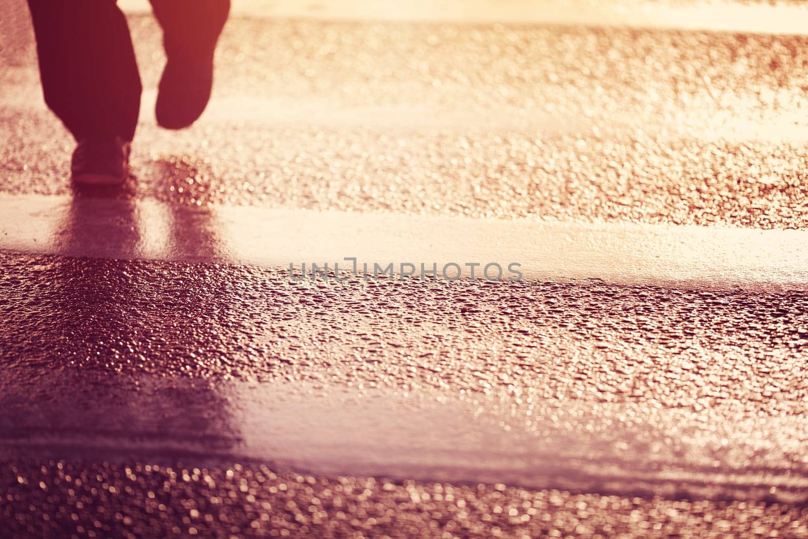 Person silhouette walking on the pedestrian way. Man passing the road in early morning