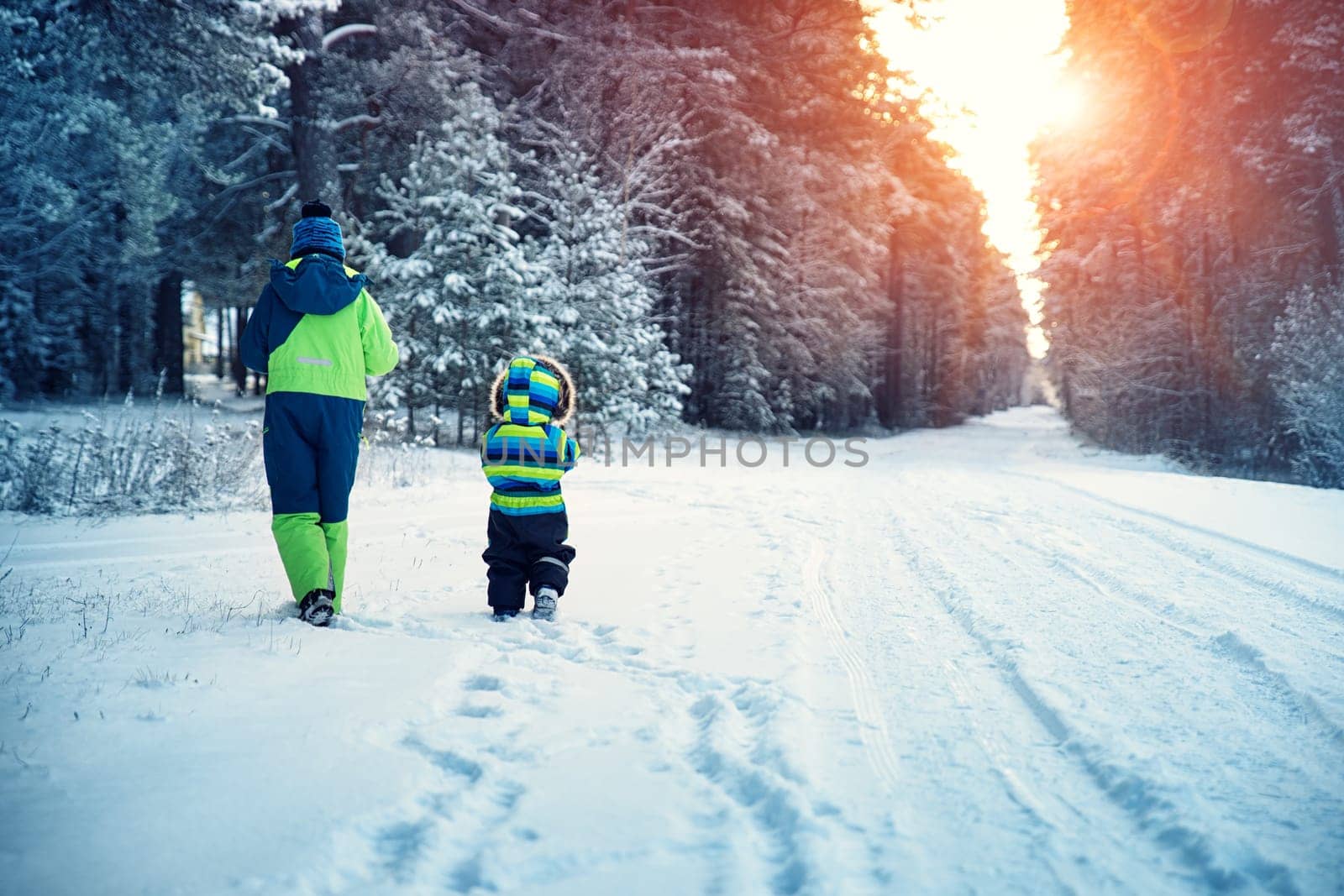 Children walking on snow at snowfall. Boys in winter clothes outdoors in cold weather