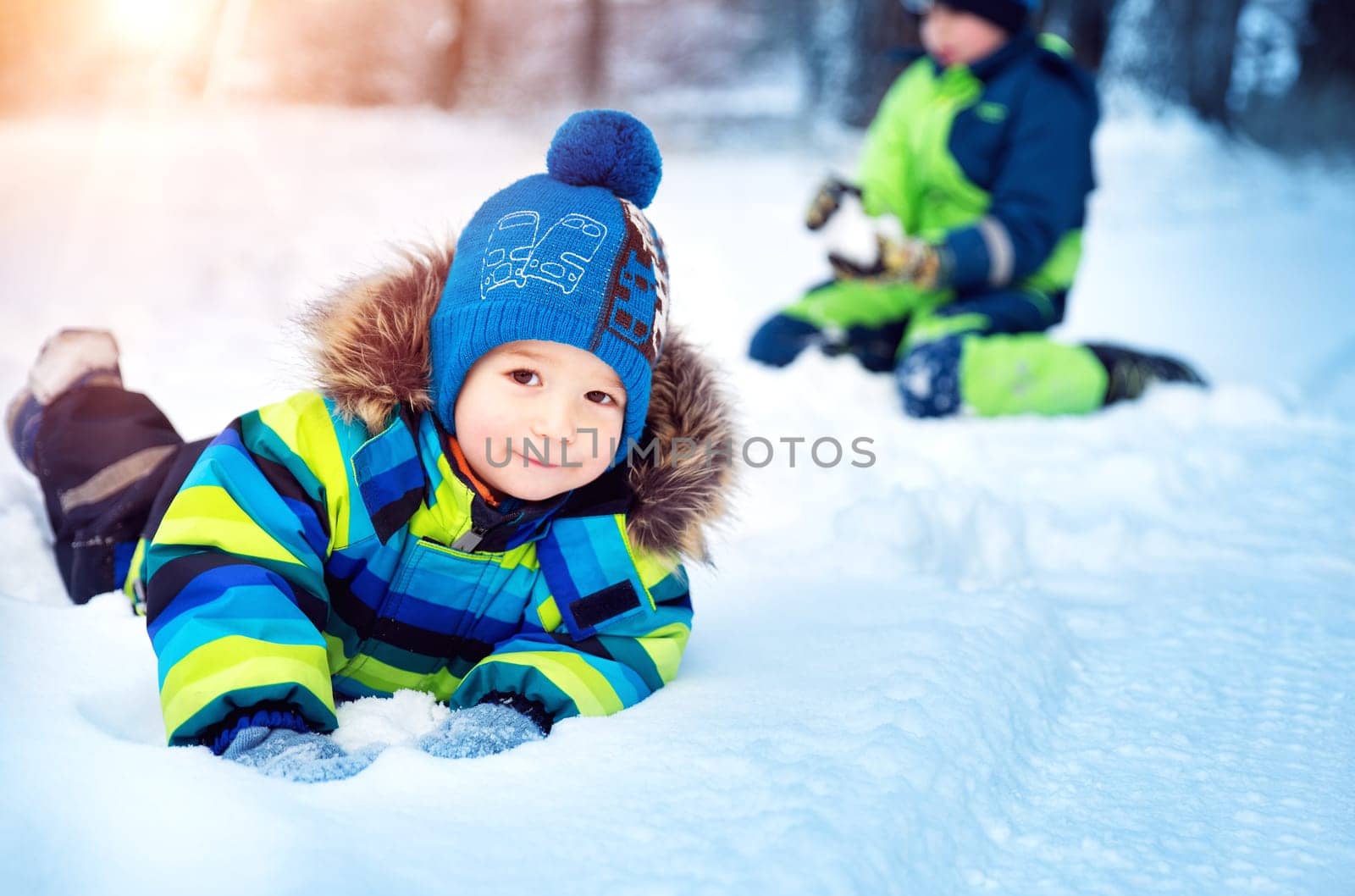 Children playing in snow at snowfall. Boys in winter clothes outdoors in cold weather