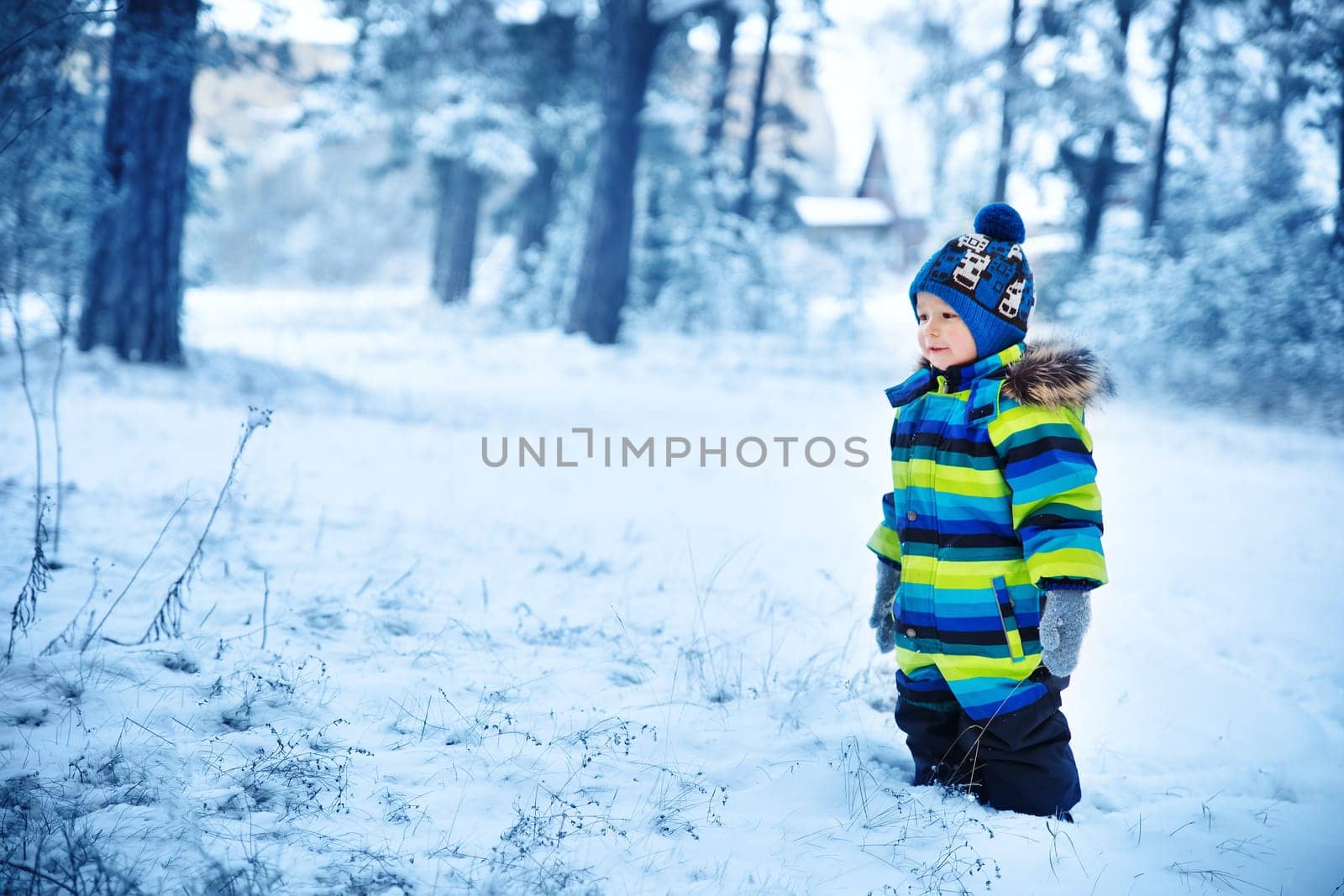 Baby boy smiling at snowfall. Child in winter clothes