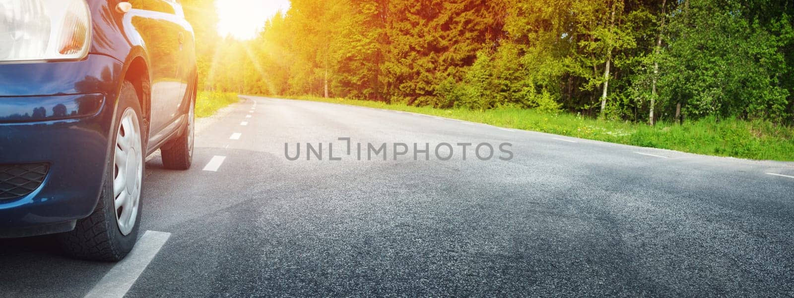 Car on asphalt road on summer day at park. Transportation panoramic background with sunlight