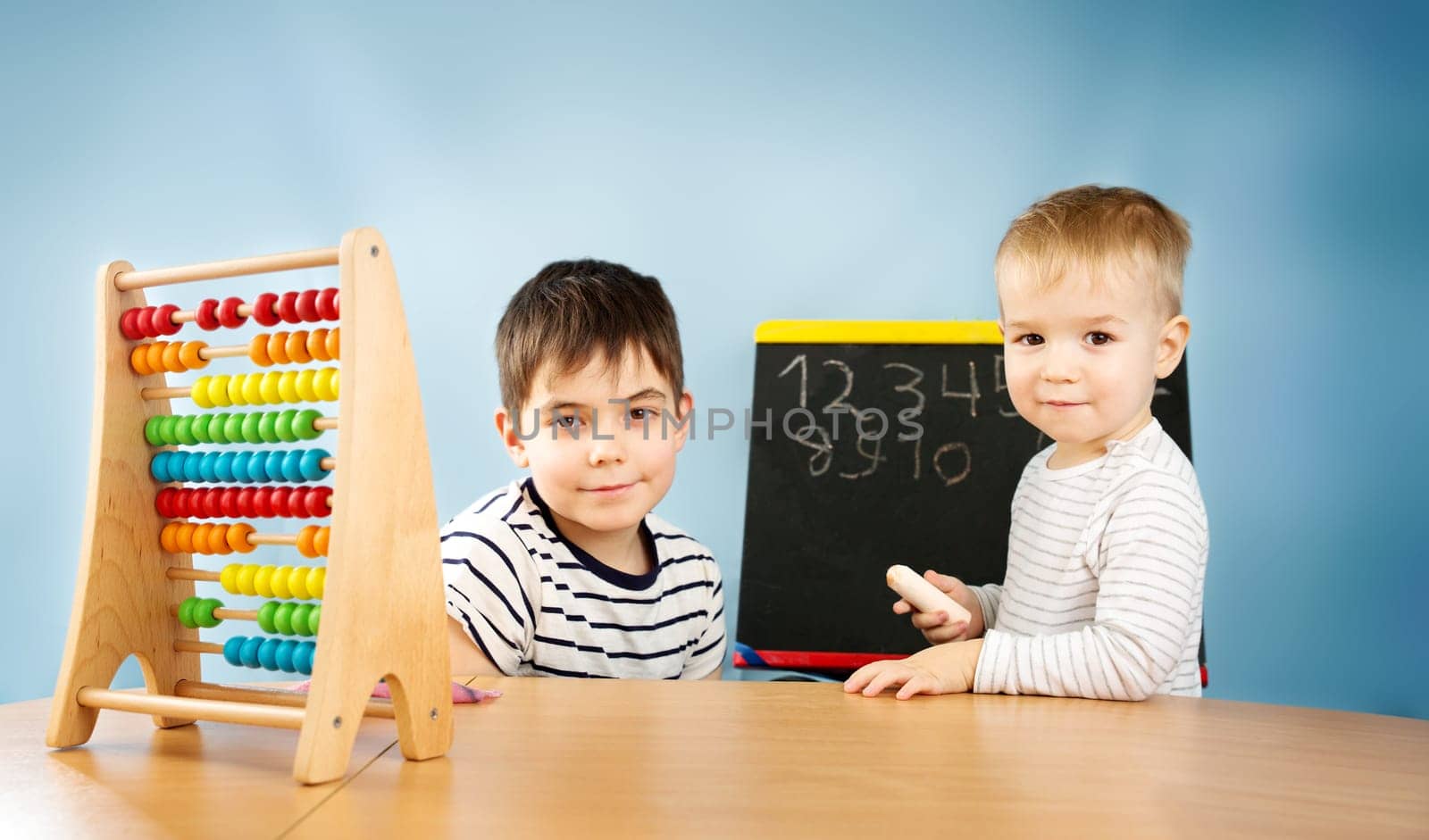 Children writing numbers on chalkboard. Boys studying