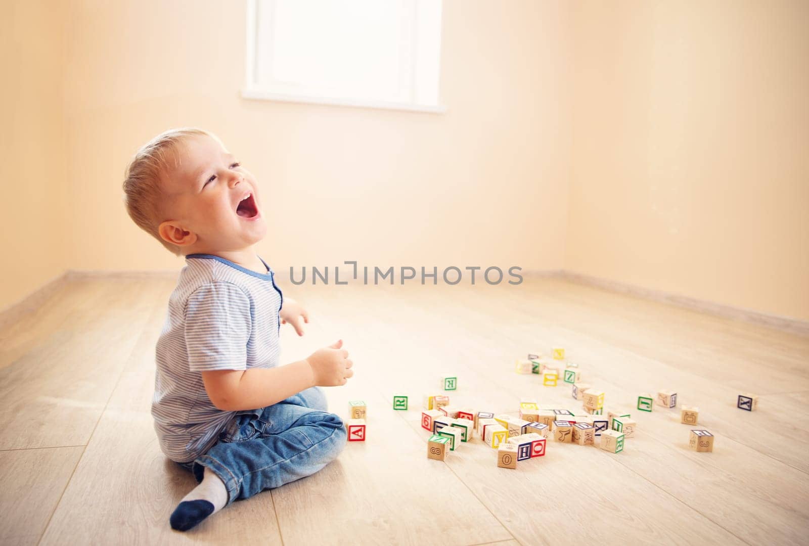 two years old child sitting on the floor. Pretty little boy palying with wooden cubes at home