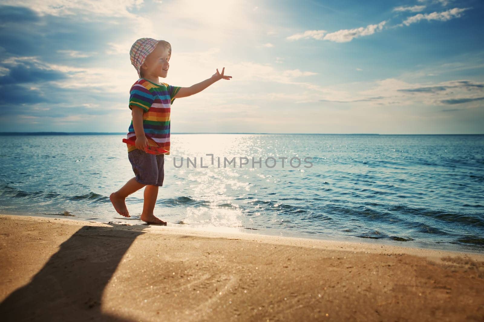 Baby boy playing with ship toy at sea. Child os on vacation in summer at the beach on vacations