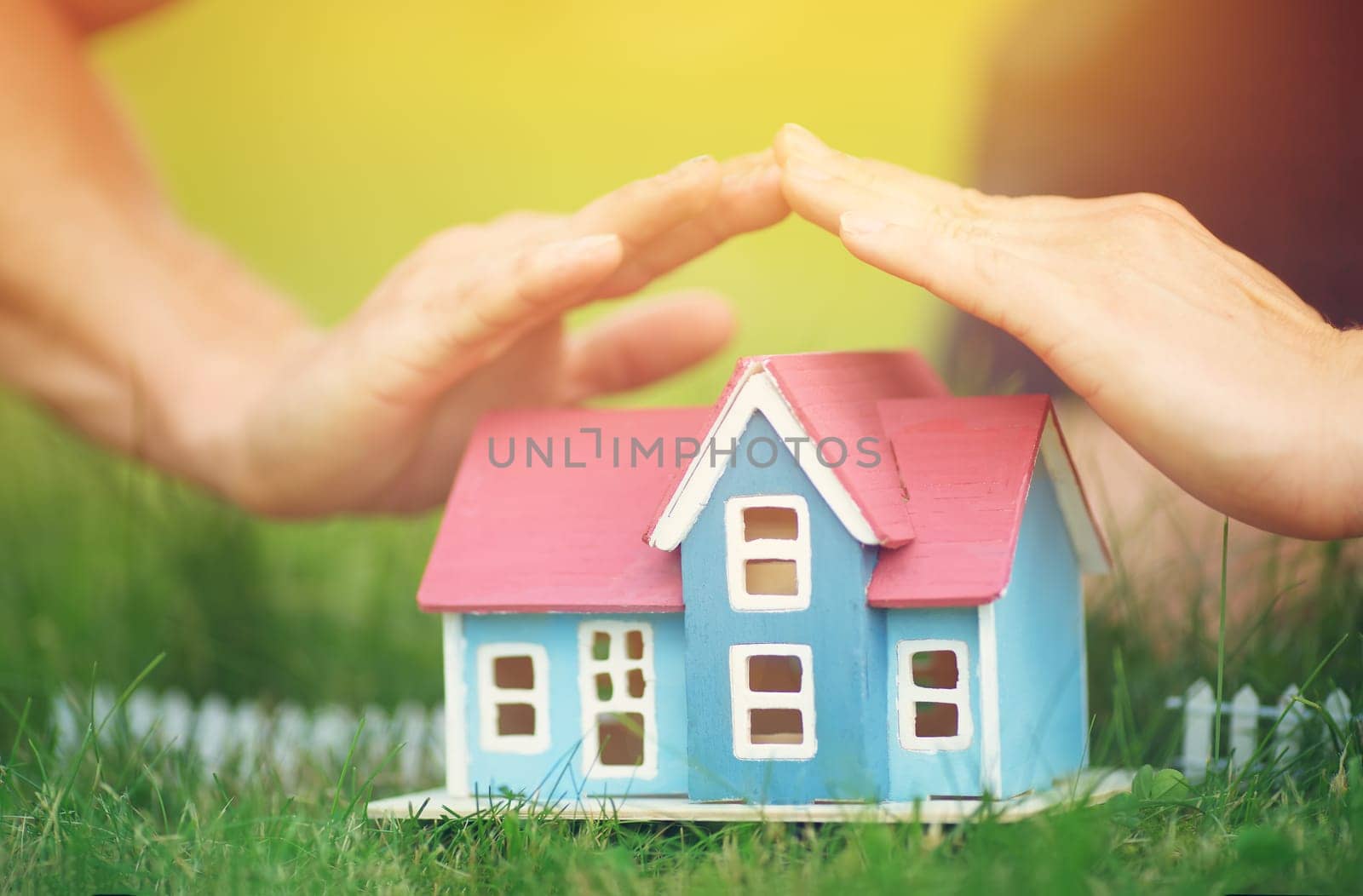 man hands holding wooden house on the grass