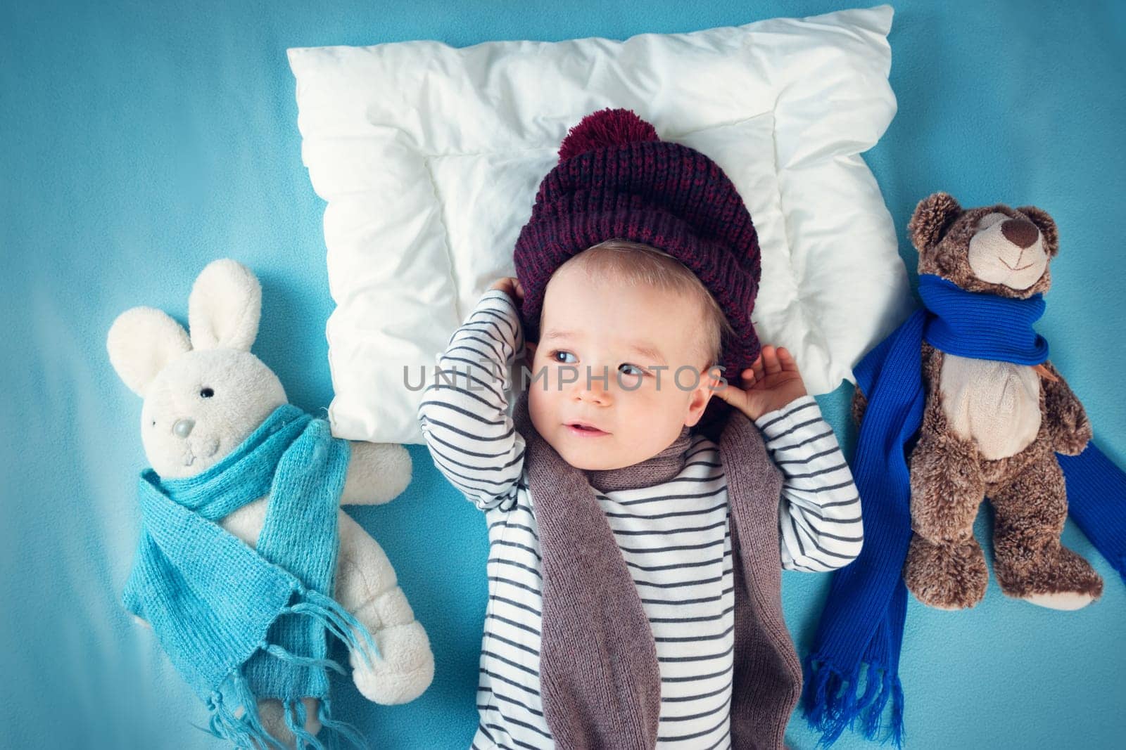 Ill boy lying in bed. cute child with fever and hat on head