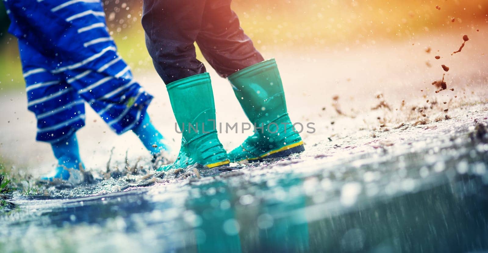 Child walking in wellies in puddle on rainy weather. Boy under rain in summer