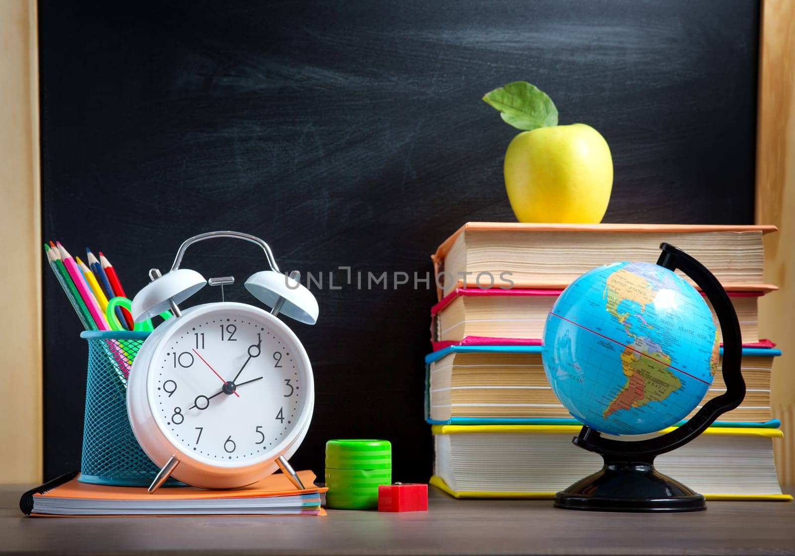 school accessories on the table with blackboard background. Pencils and books