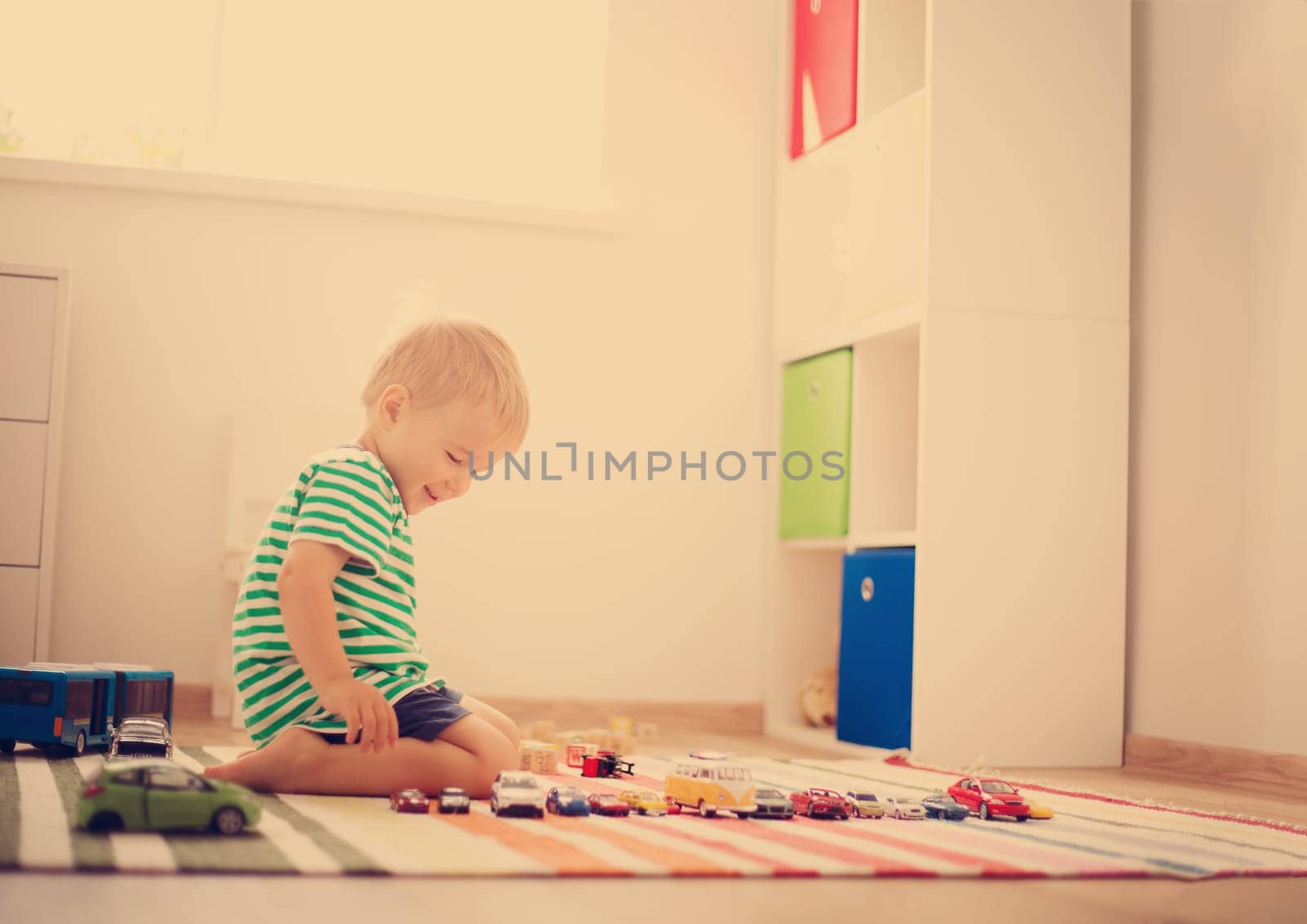 Little child playing with toy cars. Boy sitting on the floor at home