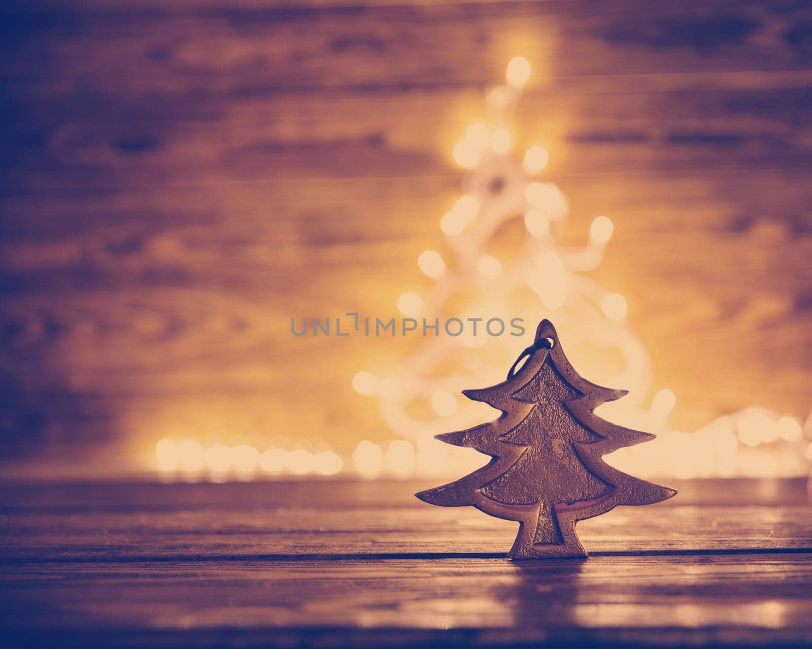Fir tree toy on wooden background with christmas lights.