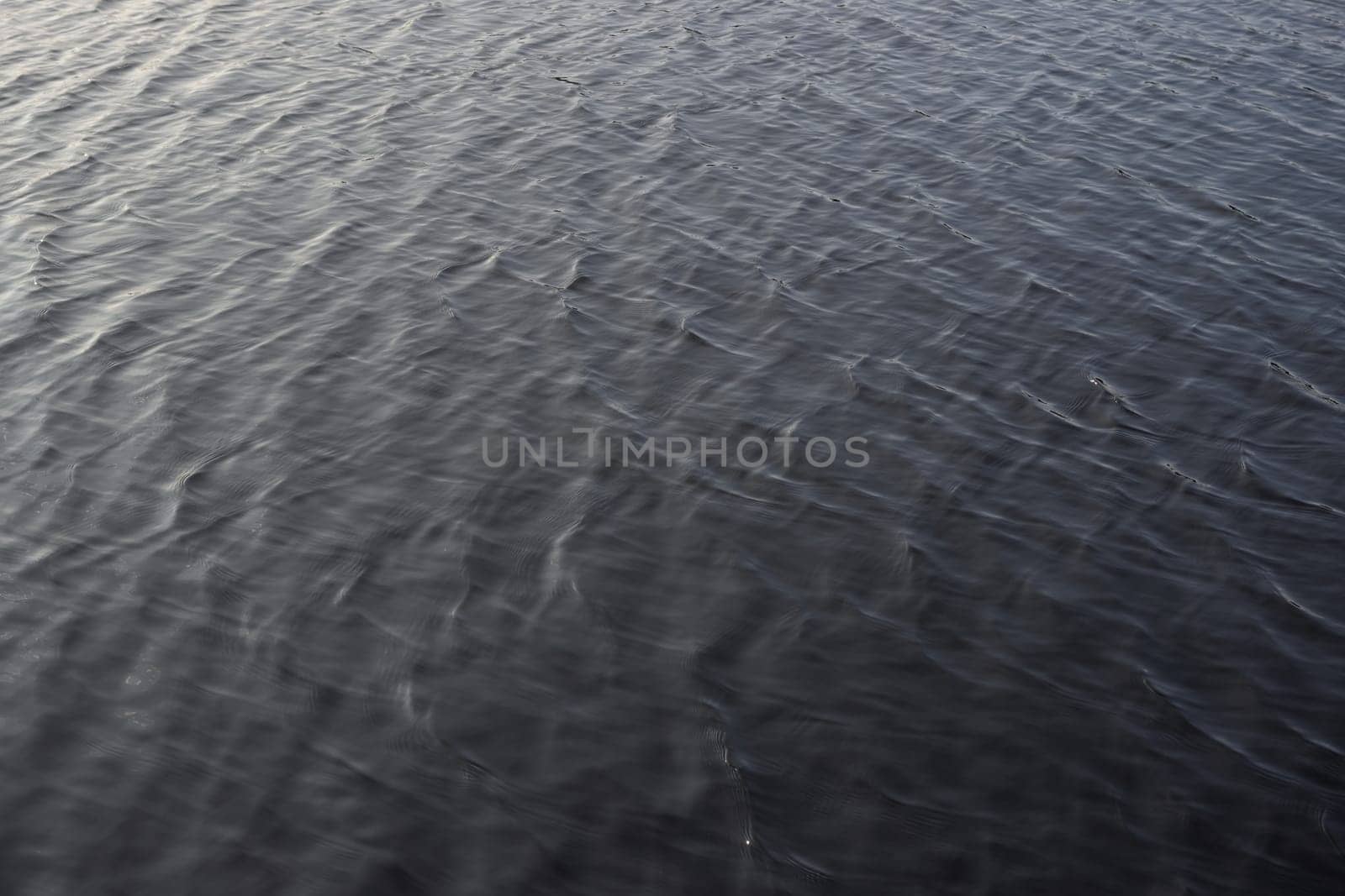 2 - Full frame gently rippled lake water. smooth sunlight gives gradual colors across the frame. Waves not cresting, evening daytime sunlight.