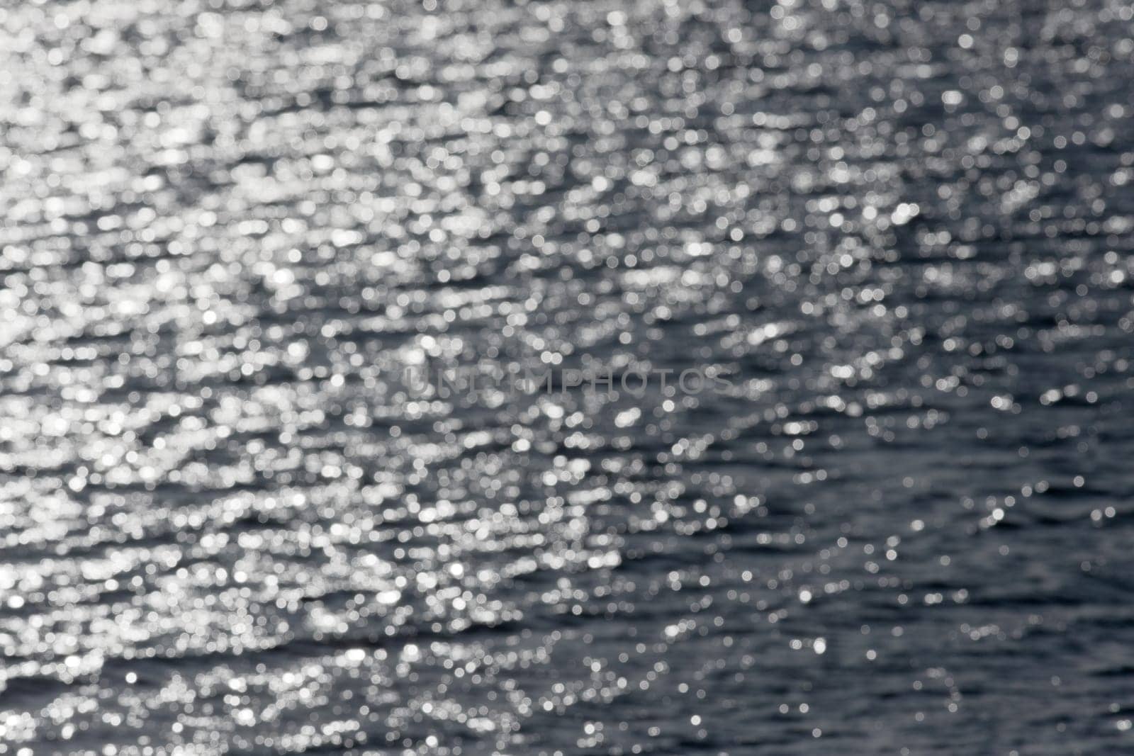6 - Out of focus sunny water forms a pleasing smooth abstract background of lens effect bokeh. Water lake theme, outdoors image, into the sun.